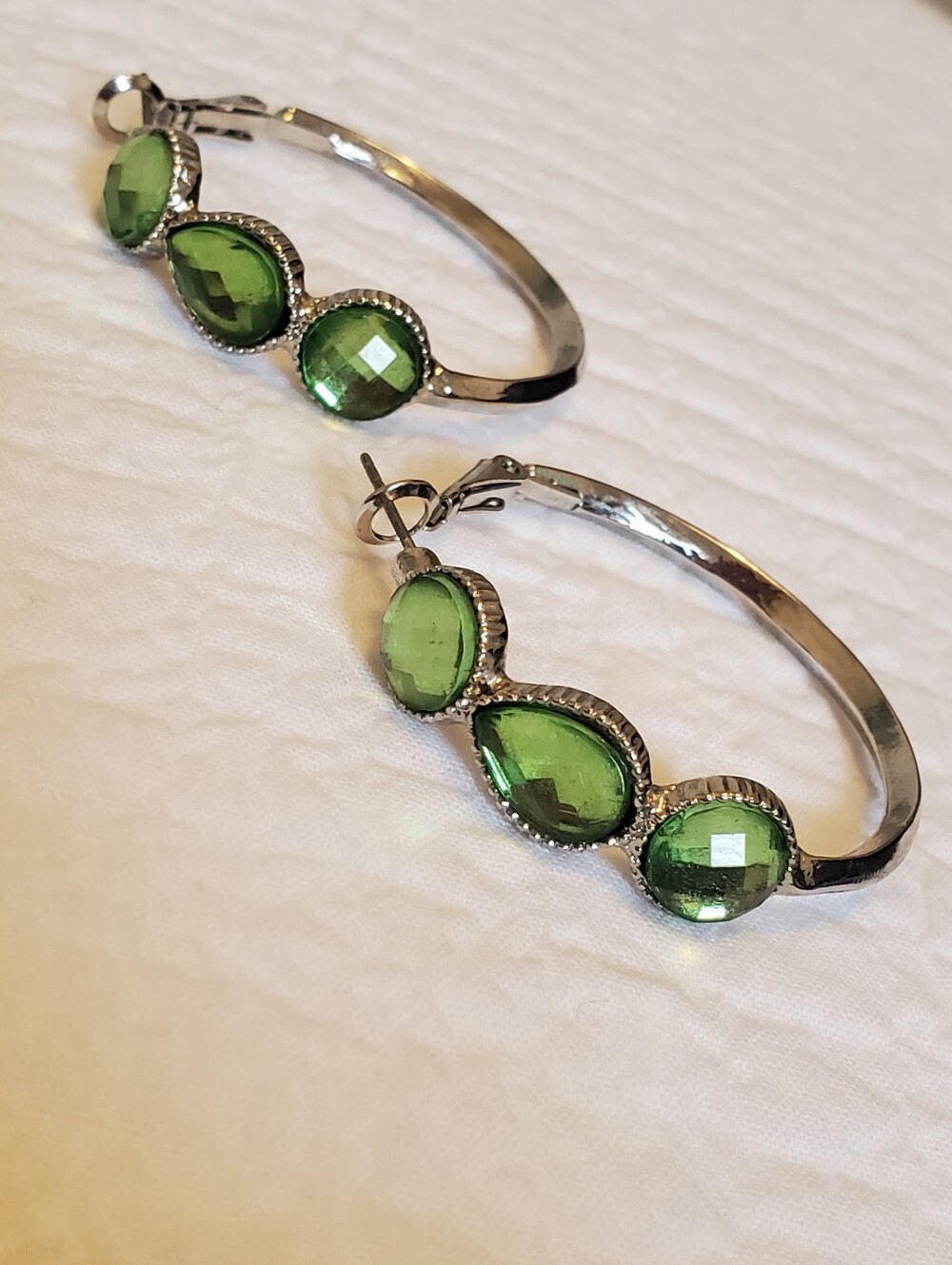 Silver-tone hoop earrings featuring 3 green faceted crystals in bezel settings